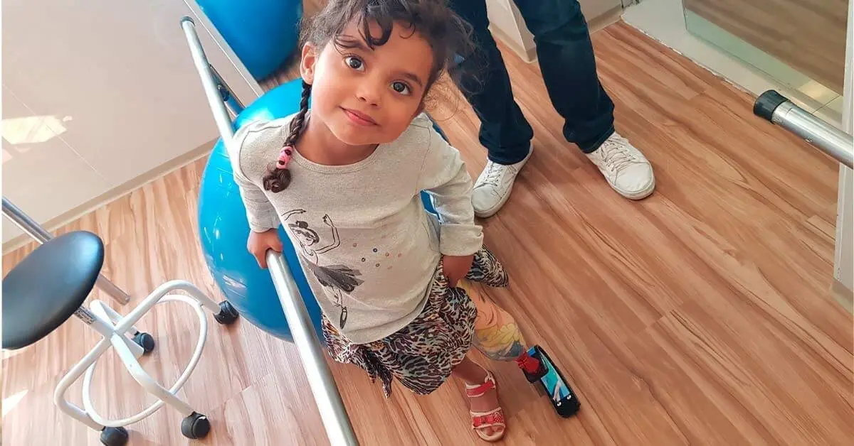 Menina pequena com prótese de perna em sala de fisioterapia