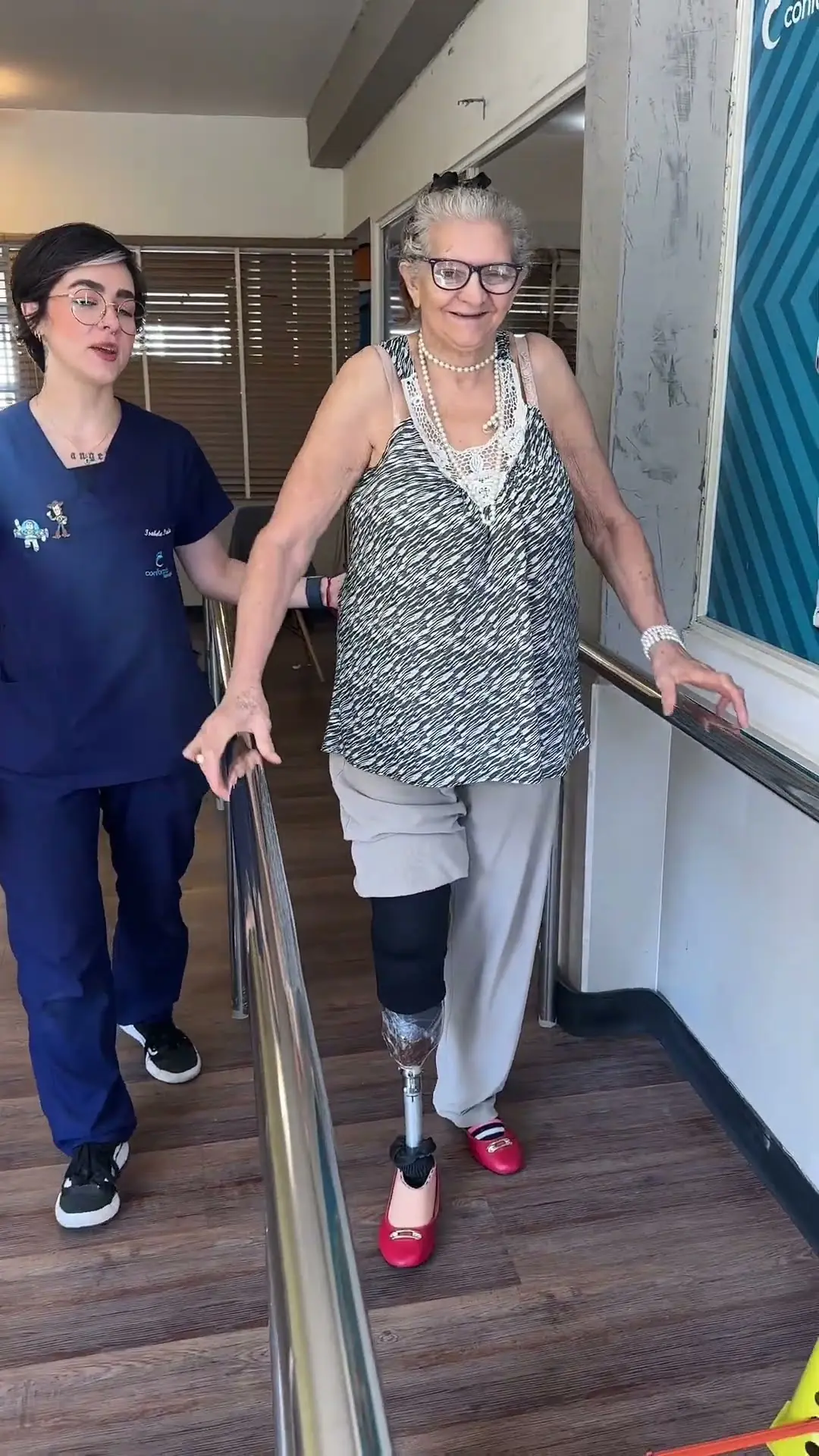 Dona Irene caminhando nas barras paralelas com a fisioterapeuta