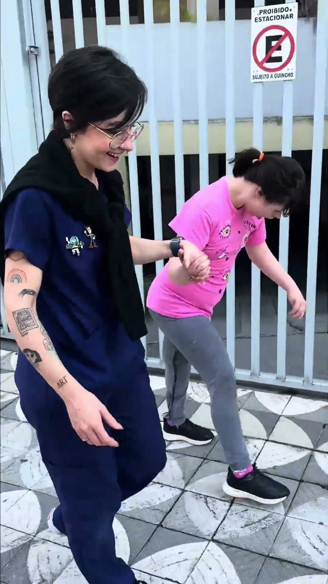 Isabela caminhando na rua com a fisioterapeuta
